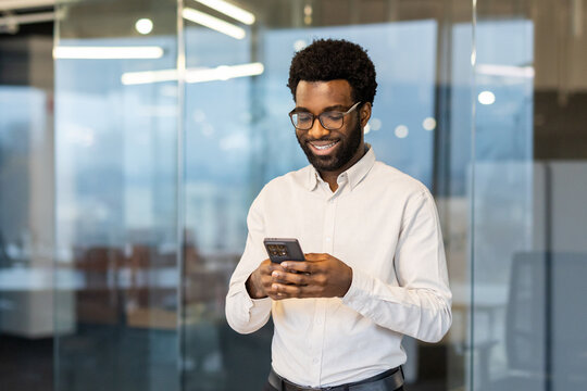Smiling professional in a modern office using a smartphone during a break
