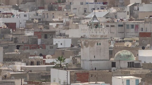 Tower of historic mosque surrounded by traditional homes in narrow alleys of old medina in Sousse, architecture and religion in Tunisia
