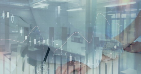 Doctor with stethoscope typing and jotting at desk with laptop and clipboard financial charts