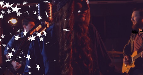 Singing female vocalist wearing knit cap, dark coat on stage, with vintage mic, star graphics
