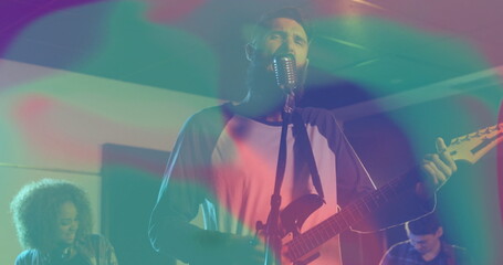 Performing bearded vocalist and guitarist strumming guitar singing on small stage, retro microphone