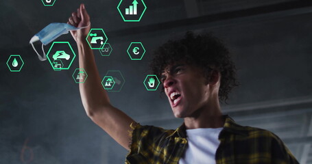 Shouting man wearing plaid shirt holding mask in industrial hall with holographic icons, copy space
