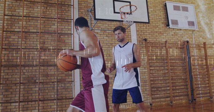 Maroon jersey player holding basketball near hoop in school gym, with defender and climbing frames