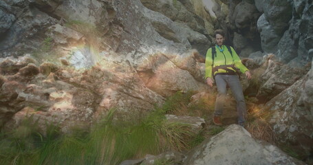 Obraz premium Hiker navigating gorge wearing green jacket harness belt backpack boots jagged rocks, copy space