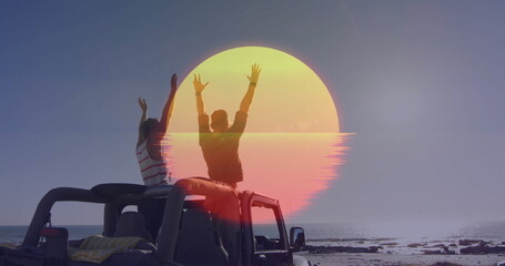 Obraz premium Raising arms two men celebrating at rocky shoreline, with open-top jeep, blanket and stylized sun