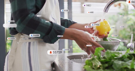 Woman wearing plaid shirt rinsing bell pepper at kitchen sink, with digital notification bubbles