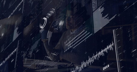 Mid-adult man wearing sweater studying holographic data overlays in modern office, with coffee mug