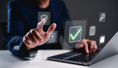 A person interacts with digital icons, highlighting security and verification, in a modern workspace with a laptop.