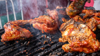 chicken meat that has been seasoned with sauce and is being grilled