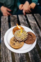 Warm Birthday Celebration with Assorted Cookies and Candlelit Ambience on Rustic Wooden Table