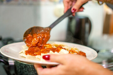 Chef pouring red meat sauce on ravioli for lunch preparation