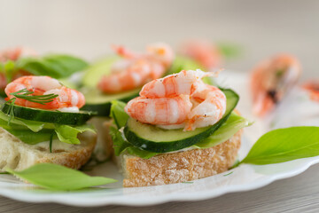Portioned appetizers with shrimps, lettuce and sauce on a wooden table