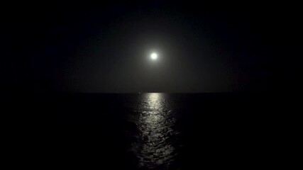 Moon casts a serene glow over tranquil sea surface at night. - Powered by Adobe