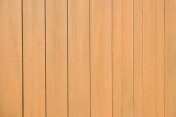 Naklejka premium Vertical wooden boards painted in a light tan color form a smooth, uniform fence surface under direct sunlight.