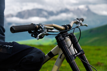 Handlebars of a bicycle against the backdrop of an epic mountain landscape. Mountain bike concept