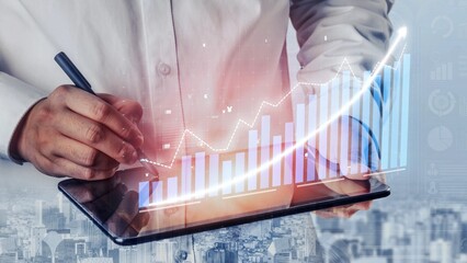 A business professional focuses on analyzing data trends using a digital tablet in a modern office. Financial growth is visually represented through statistics graphics. Copula