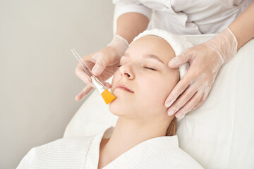 Young caucasian female receiving facial treatment at spa by gloved professional.