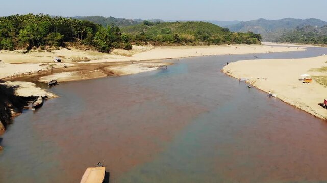 Lala Khal, Bangladesh - 22 August 2025: Aerial view of the river, showcasing the sandy banks meeting the clear water, surrounded by lush green hills.