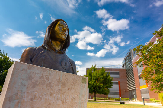 Budapest, Hungary - July 04, 2024: Satoshi Nakamoto monument with Microsoft office in the background. Sunny summer dear, medium cloudy sky.