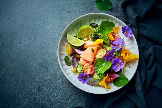 Cherry tomato and salmon salad with edible flowers and parmesan dressing Top view. Healthy lifestyle