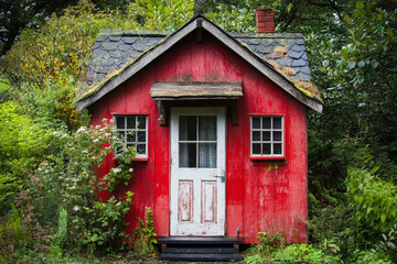 Red wooden cabin nestled in lush green foliage charming rustic retreat