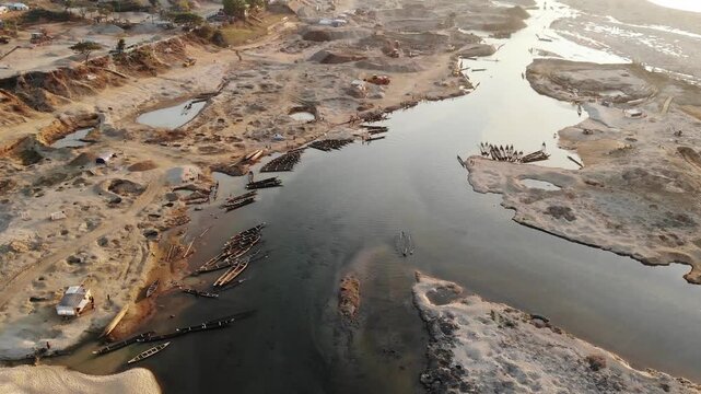 Jaflong, Bangladesh - 21 August 2025: Aerial view of numerous wooden boats docked along the riverbank, contrasting with the sandy terrain and clear water.