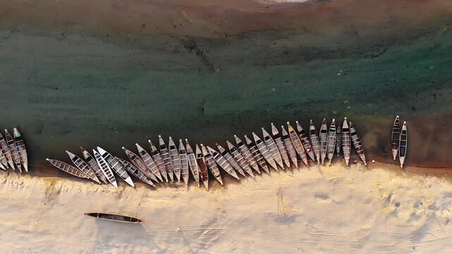 Jaflong, Bangladesh - 21 August 2025: Aerial view of numerous boats lined up on the beach where the sand meets the clear, shallow water.
