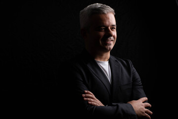 Fototapeta premium Artistic portrait of grey-haired businessman, low key lighting on black