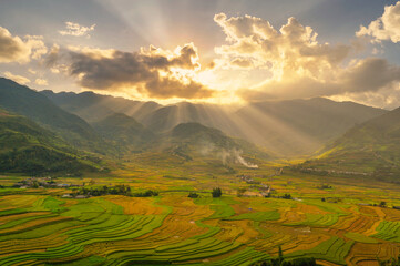 Dramatic sky with sunlight beaming through the clouds over mountain and terraced rice field landscape, Sapa, Mu Cang Chai, Yen Bai, Vietnam