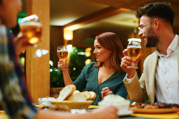 Friends enjoying beer and food at restaurant dinner