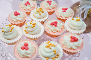 A tray of cupcakes with pink frosting and gold sprinkles