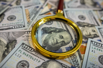 Magnifying glass over dollar bills – Financial audit, money analysis or fraud investigation concept