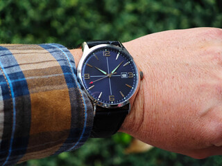 Stylish Blue Dial Watch on Male Wrist in Nature. Elegant analog wristwatch with a navy blue face and metallic silver accents