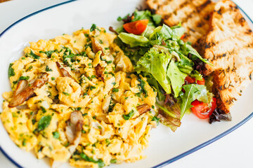 Delicious breakfast plate with scrambled eggs, greens, and grilled toast served at a cozy cafe