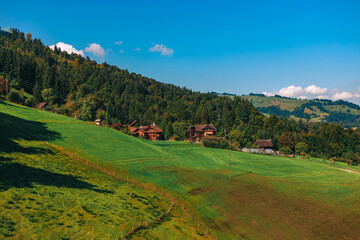 Stunning panoramic view of a cable car ascending Mount Pilatus in the Swiss Alps. The bright red gondola contrasts beautifully with the rugged mountain cliffs, lush green slopes, and distant snow-capp © Breg