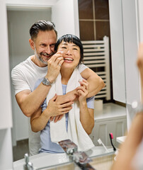 Fototapeta premium Portrait of a young couple applying cream, skincare and cosmetic, in front of mirror in bathroom. Dental hygiene, youth, love and beauty concepts