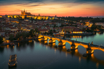 Breathtaking drone panorama of Prague at sunset, featuring Prague Castle and Charles Bridge glowing in golden light over the Vltava River, blending history and beauty from above.