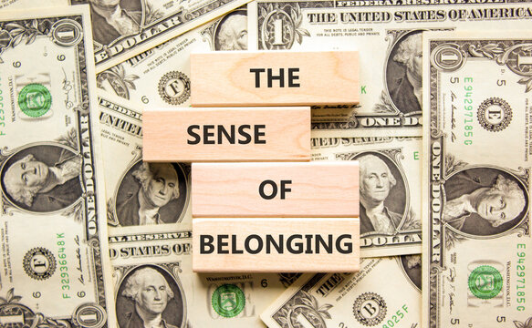 The sense of belonging symbol. Concept words The sense of belonging on beautiful wooden blocks. Beautiful background from dollar bills. Business and the sense of belonging concept. Copy space.