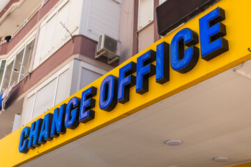 Obraz premium A vibrant yellow sign reading CHANGE OFFICE catches attention in an urban location