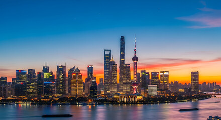 Naklejka premium Modern city skyline illuminated at dusk with vibrant sunset colors over water