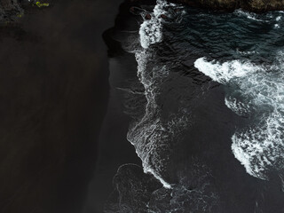 Drone captures El Ancon Beach in Tenerife, Spain, highlighting the striking contrast between dark...