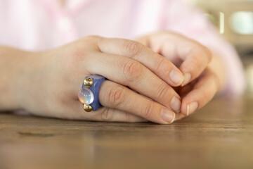 A Hand Adorned with a Unique Blue Resin Ring Featuring an Iridescent Cabochon and Gold Bead Accents