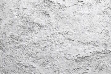 A textured monochrome image of a roughly plastered wall, showing varying shades of grey and white, with an uneven, heavily textured surface