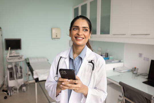 Happy Indian doctor woman using online service on mobile phone