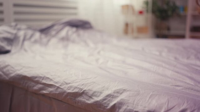 Woman making bed with fresh linen, adjusting blanket on clean and tidy bed