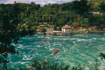 Majestic view of Rhine Falls, the largest waterfall in Europe, located near Schaffhausen in northern Switzerland. Powerful cascades of water rush over rugged rocks, surrounded by lush greenery and mis © Breg