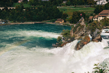 Majestic view of Rhine Falls, the largest waterfall in Europe, located near Schaffhausen in northern Switzerland. Powerful cascades of water rush over rugged rocks, surrounded by lush greenery and mis © Breg