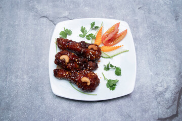 Glazed Chicken Drumsticks glazed with Sweet and Spicy Sauce with Cashews and Fresh Veggies in plate top view of Asian food
