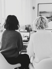 Black and white photography of women working | Two women with short wavy hair sitting at laptops in bright interior | Modern monochrome office style | Editorial work lifestyle stock image