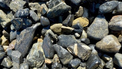 smooth wet river stones with natural gray and golden tones creating organic mineral background texture for design or nature concept